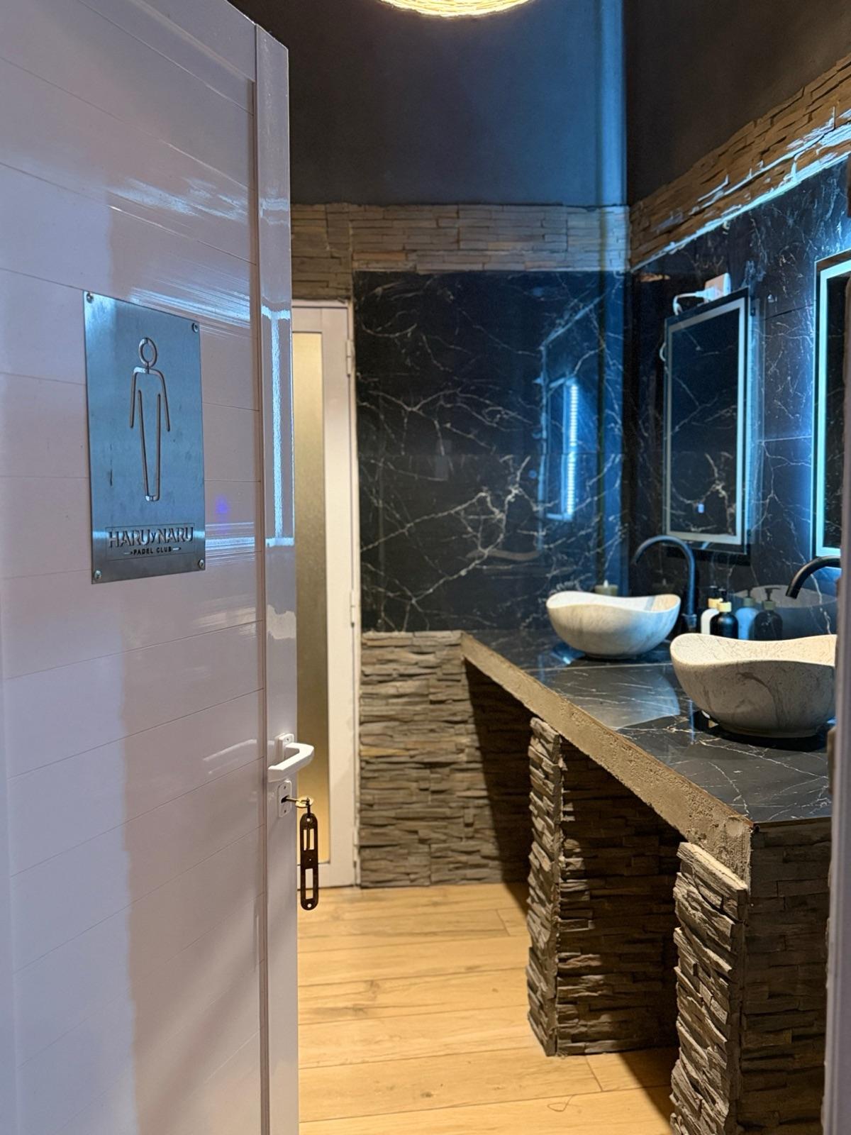 Puerta del baño de hombres con cartel de Haru y Naru