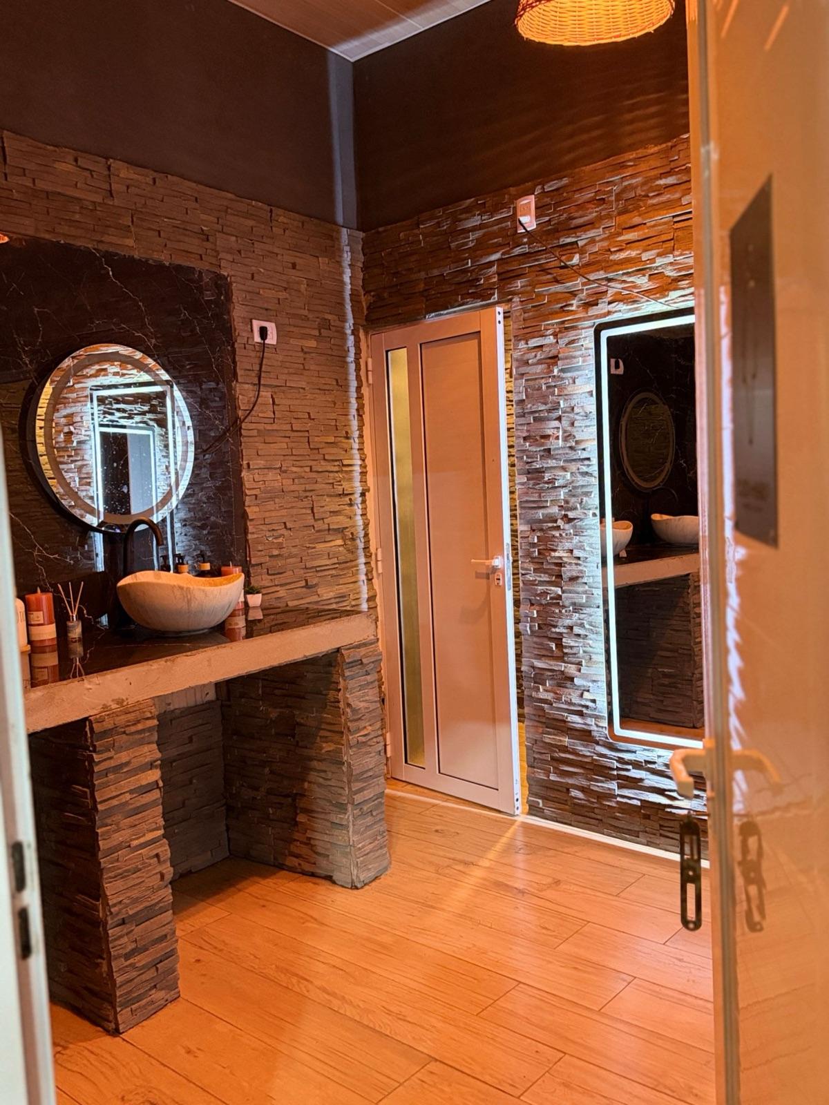 Baño de mujeres con revestimiento de piedra y espejo iluminado