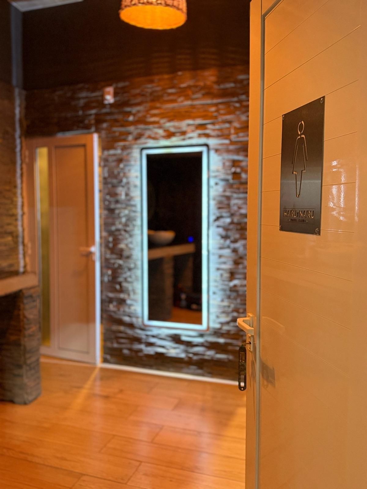 Puerta del baño de mujeres con cartel de Haru y Naru