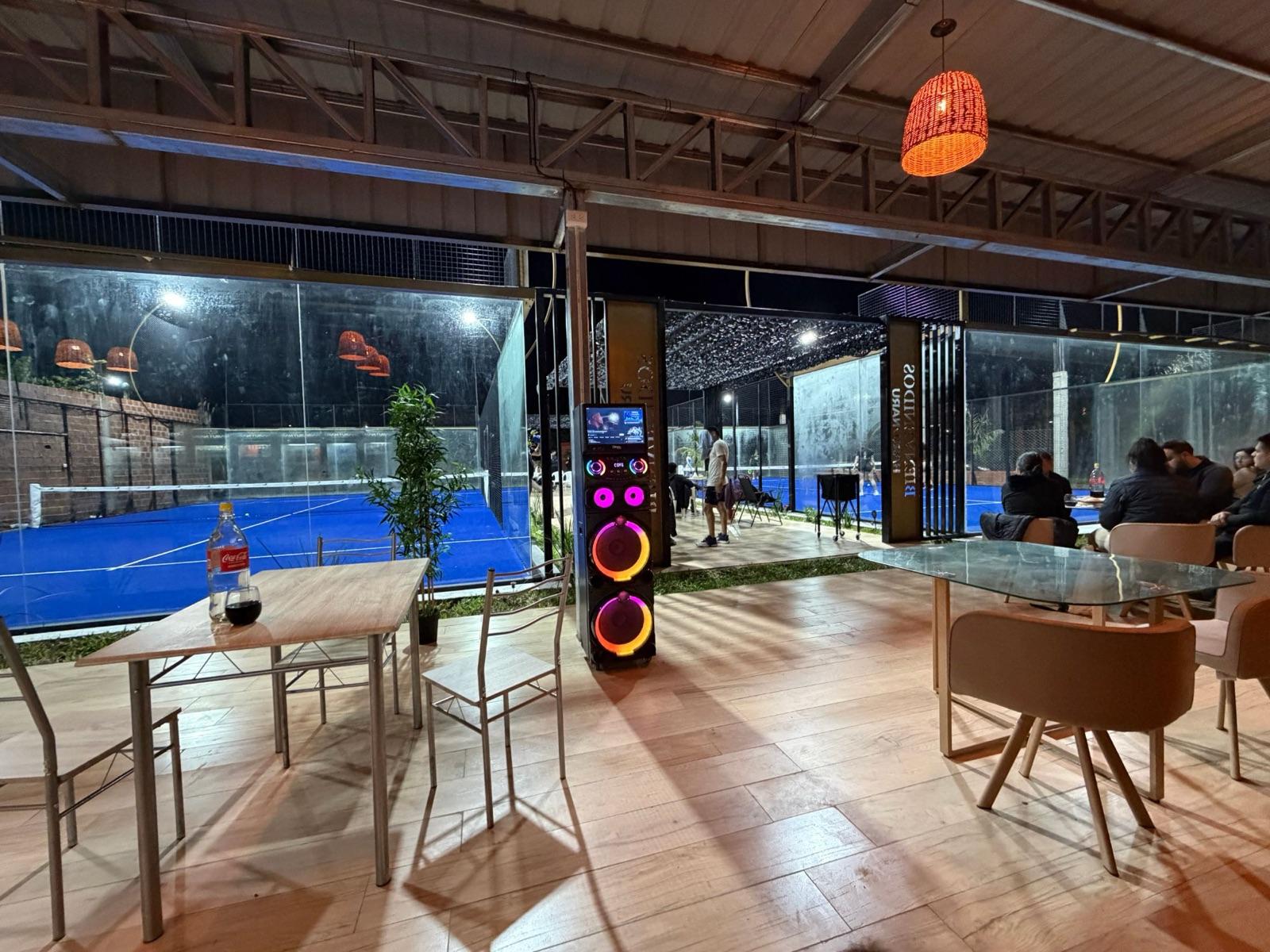 Zona de mesas con música y vista a las dos canchas